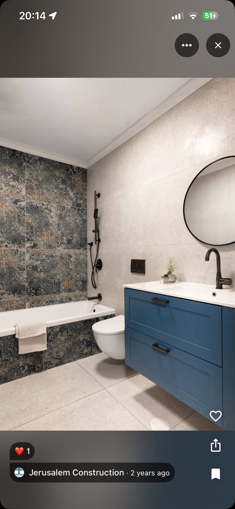 Bathroom with blue vanity, black fixtures and stone-textured tile